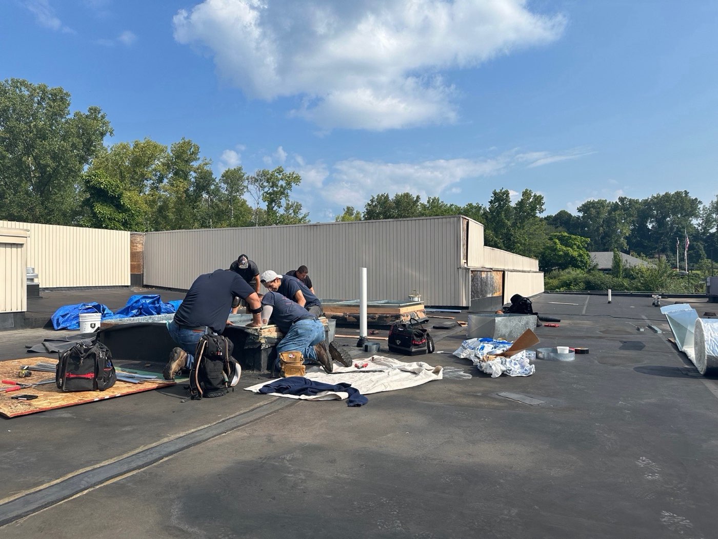 Central Air technicians setting a rooftop unit and fabricating duct on a flat roof